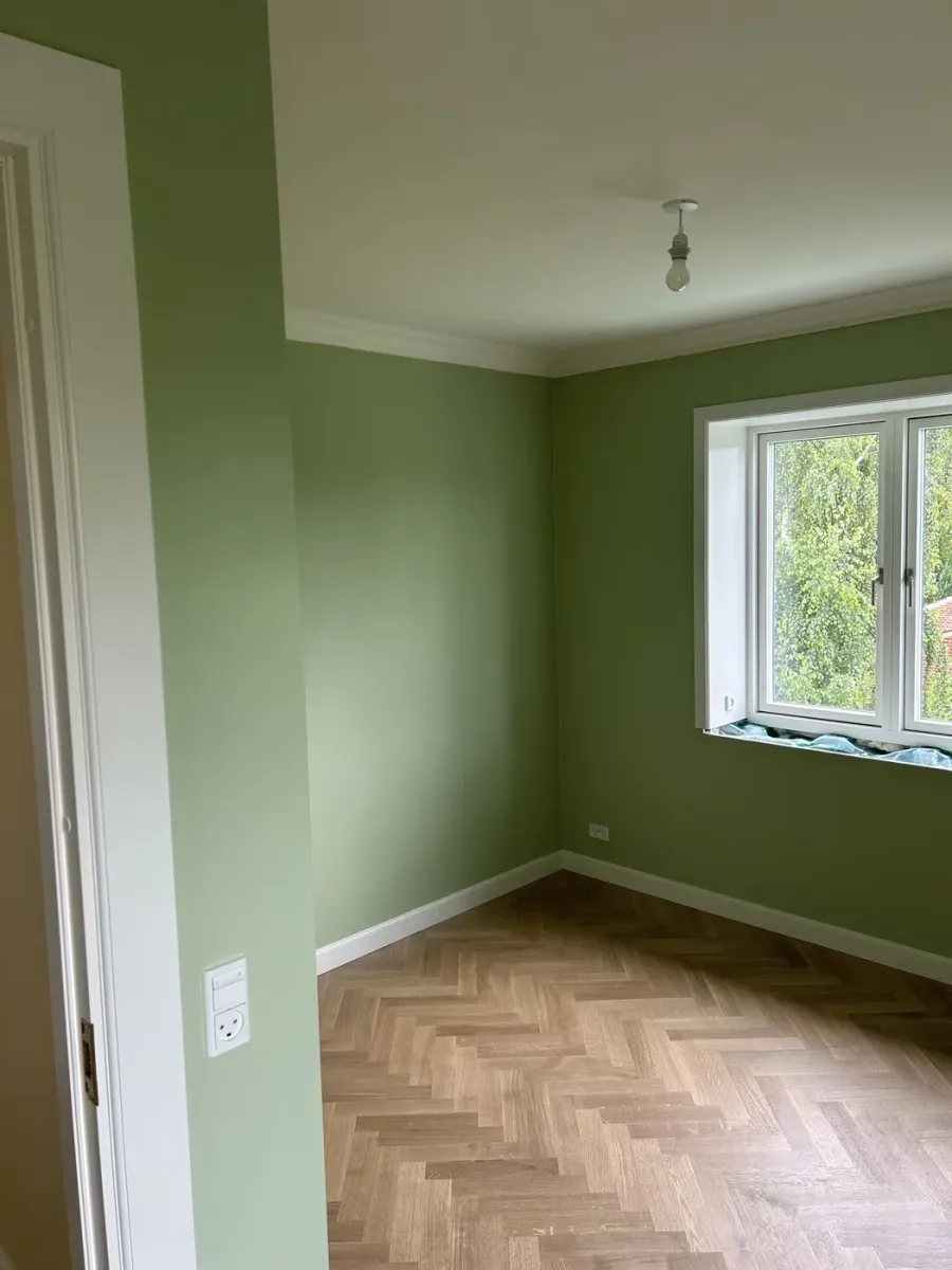 Værelse med grøn farvevæg og sildebensparket