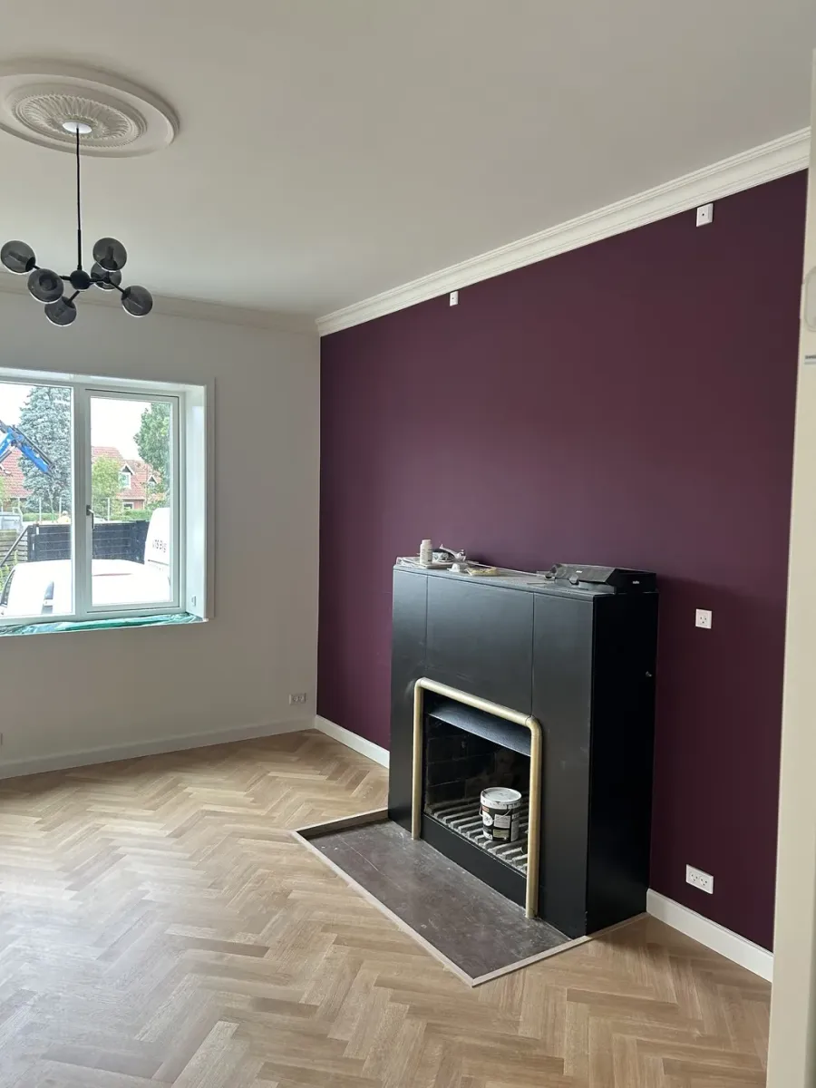 Stue med auberginefarvet væg efter indvendig renovering